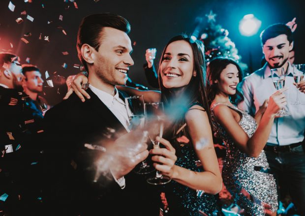 Happy Young People Dancing on New Year Party. Happy New Year Concept. Glass of Champagne. Celebrating of New Year. Young Woman in Dress. Young Man in Suit. Happy People. Modern Dances.